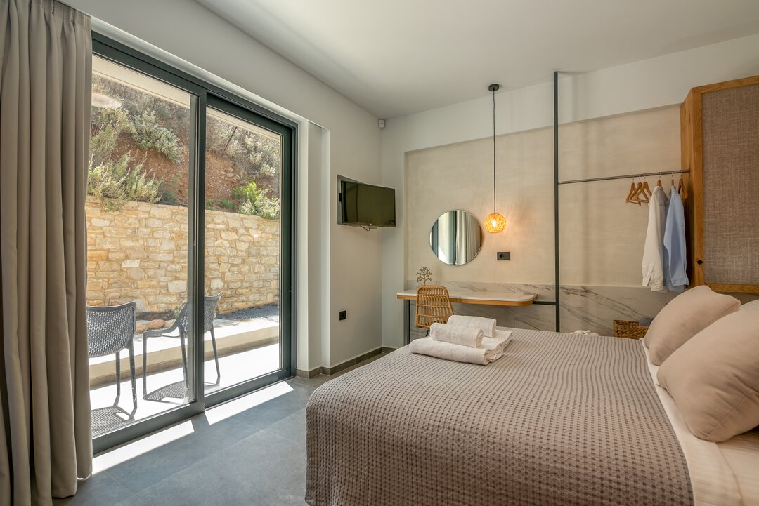 Sun-drenched bedroom with large windows, fresh white linens, and natural wood accents at Nusa Gramvousa, Kissamos, Crete
