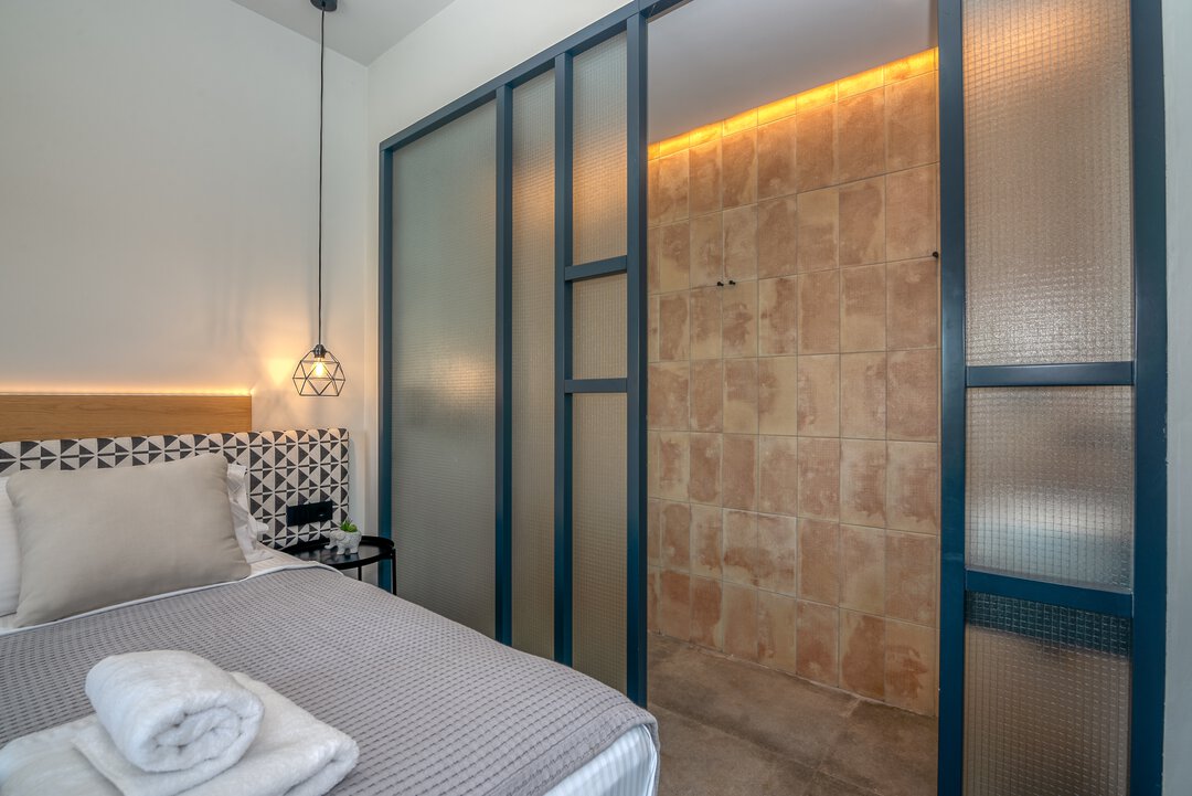 Contemporary guest bedroom with geometric headboard, ambient lighting, and modern furnishings at Nusa Falassarna, Crete