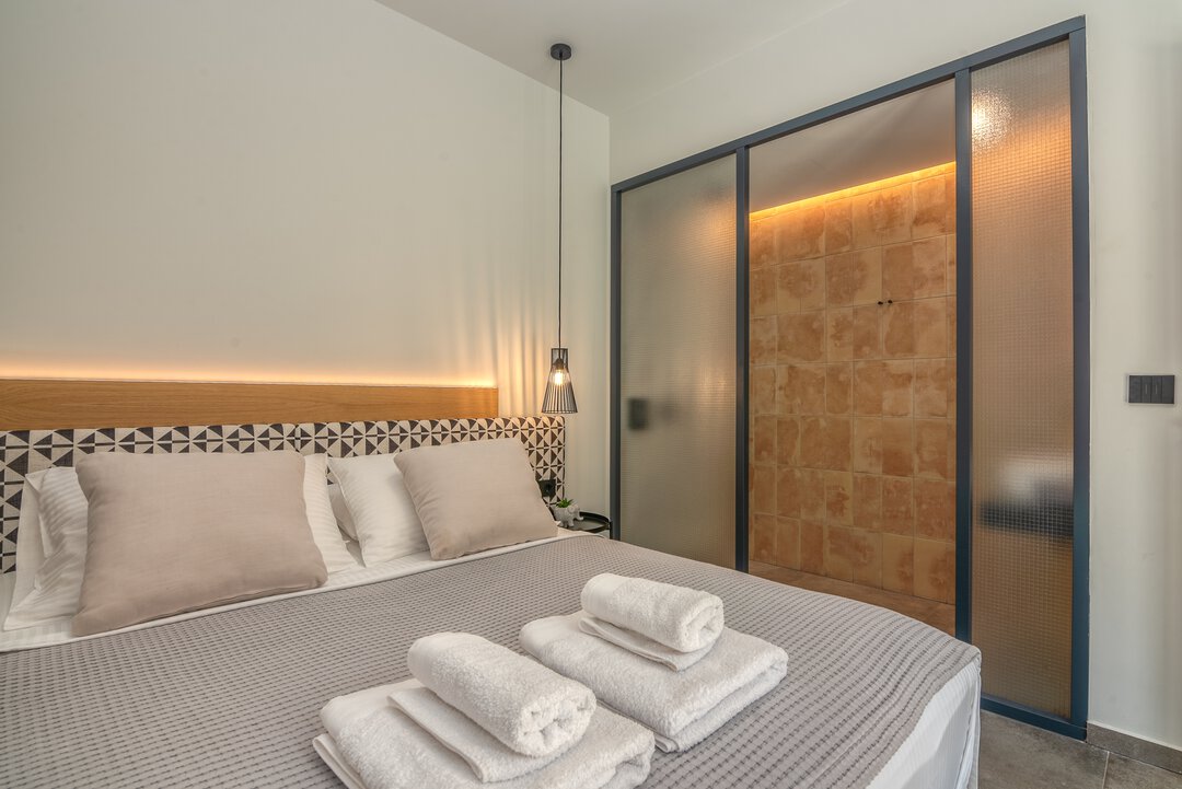 Stylish bedroom with premium bedding, designer lighting, and Mediterranean aesthetic at Nusa Balos, Crete