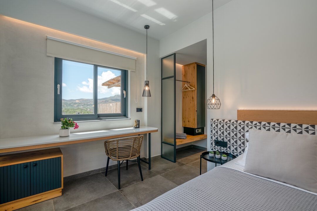 Bright bedroom with desk area, rattan chair, mountain views, and designer lighting at Nusa Balos near Balos Lagoon, Crete